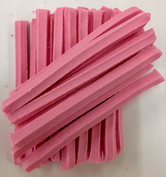 A pile of pink musk sticks candy, with a hard candy coating.